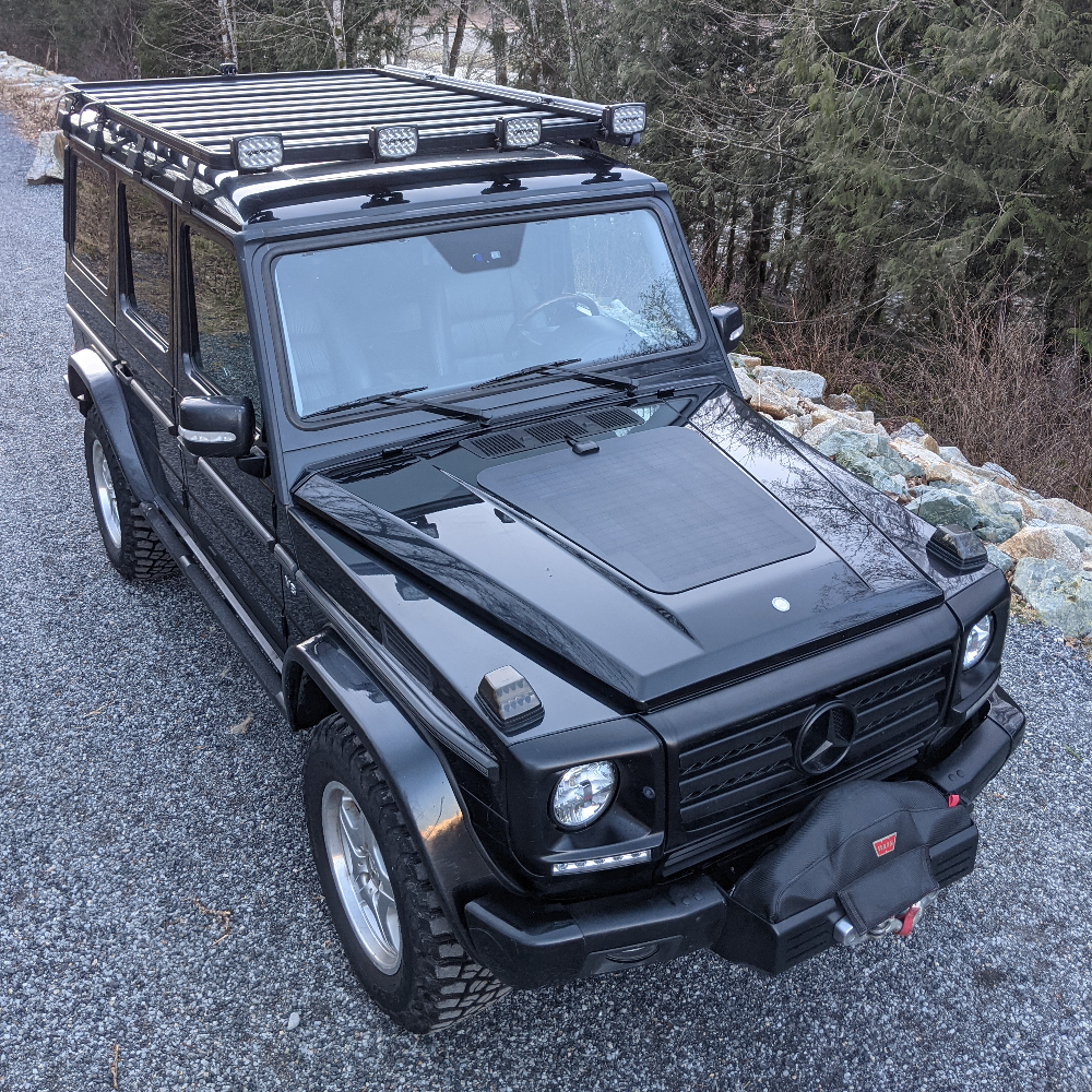 
A black mercedes-benz g-wagen wagon with a hood mounted solar panel system from cascadia 4x4, perfect for overlanding