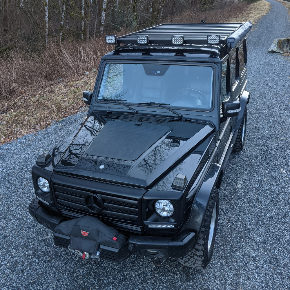 A black mercedes-benz g-wagen wagon with a hood mounted solar panel system from cascadia 4x4